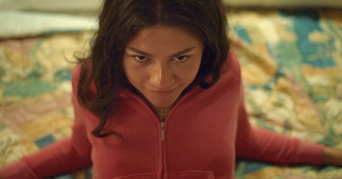 Zendaya lays on a bed in a pink hoodie in Challengers