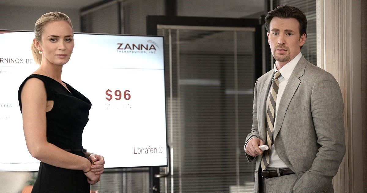 Emily Blunt as Liza wearing a black dress, and Chris Evans as Pete Brenner wearing a grey suit in front of a presentation board in Pain Hustlers