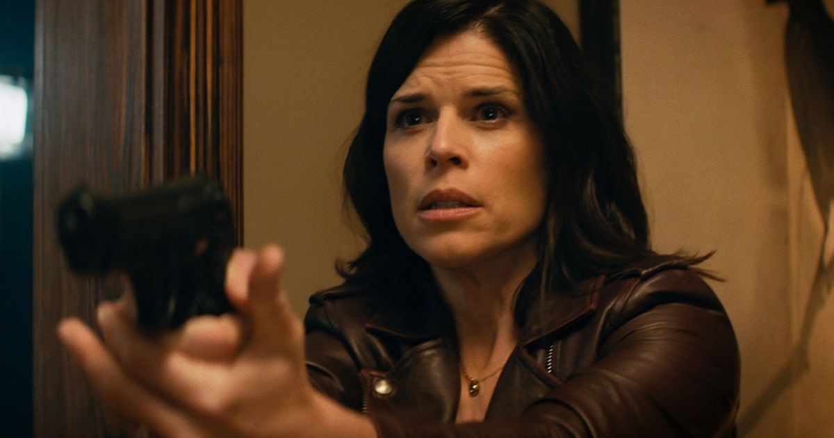Neve Campbell como Sidney Prescott, vestindo uma jaqueta de couro marrom segurando uma pistola e apontando para alguém fora da tela em Pânico (2022).