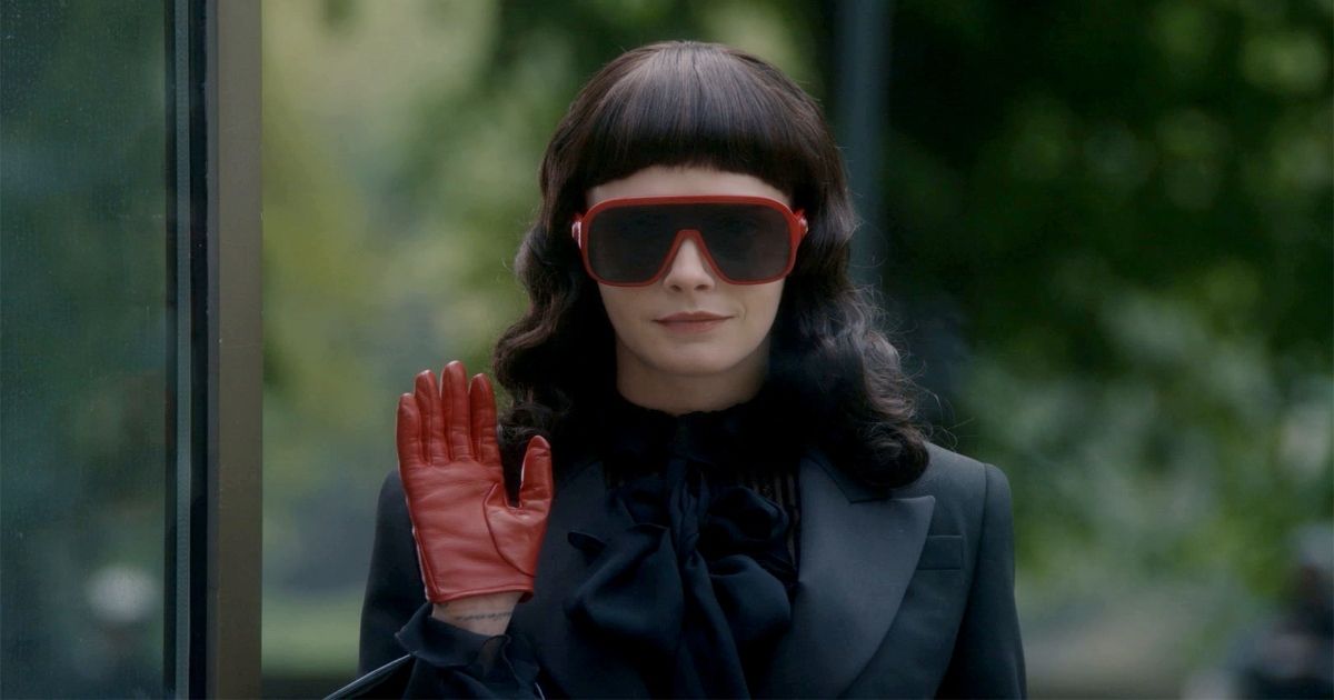 Cara Delevingne waving with a red glove and glasses in American Horror Story: Delicate