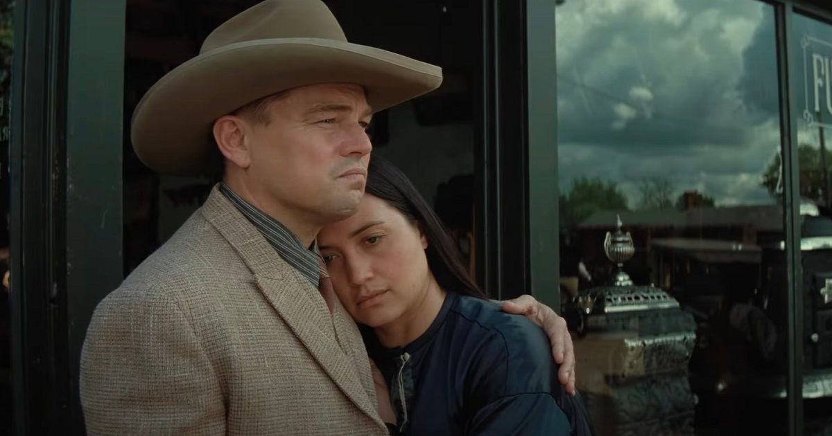 Leonardo DiCaprio wearing a cowboy hat as Ernest with Lily Gladstone as Mollie hugging him in Killers of the Flower Moon