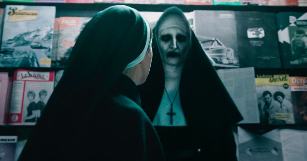 Taissa Farmiga as Irene in her nun outfit, looking at a bunch of magazines and posters with The Nun demon in front of her in The Nun II. 