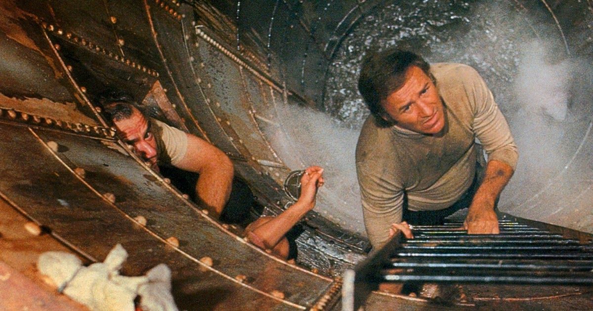 Gene Hackman climbing up a ladder while water rushes behind him in The Poseidon Adventure 