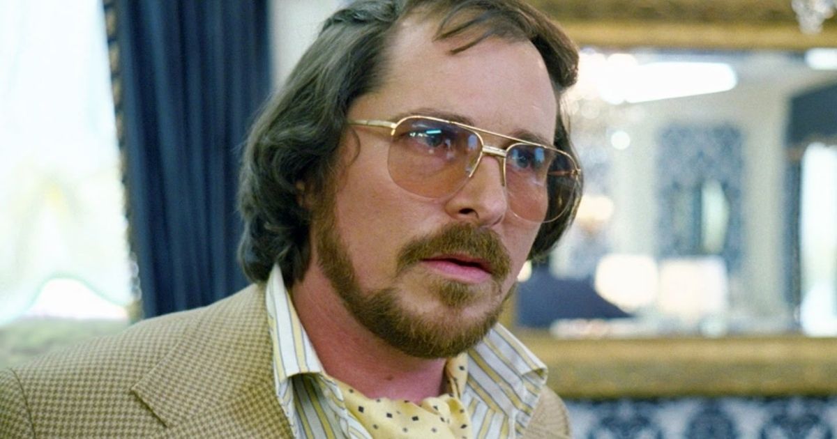 Christian Bale with sunglasses on and a yellow suit in American Hustle