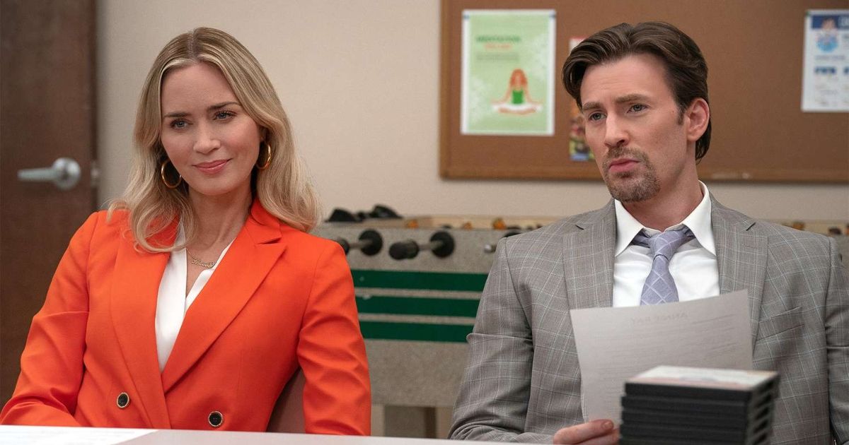 Emily Blunt and Chris Evans wearing suits, with Evans holding a paper with a foosball table in the background in Pain Hustlers.