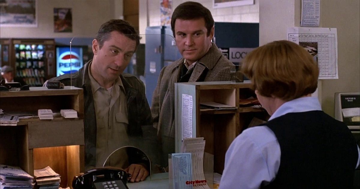 Robert De Niro e Charles Grodin conversam com um funcionário na recepção de uma empresa em Midnight Run.