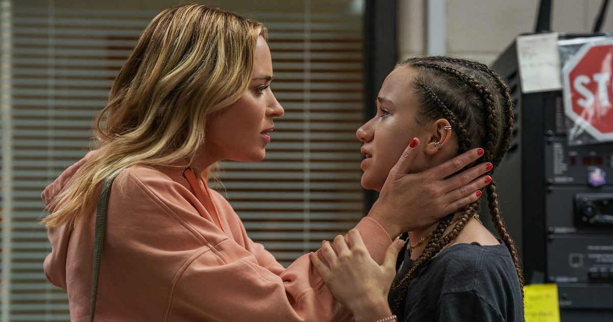 Emily Blunt as Liza wearing a peach colored hoodie, holding Choe Coleman's face, who plays Phoebe, as both of their faces look worried.