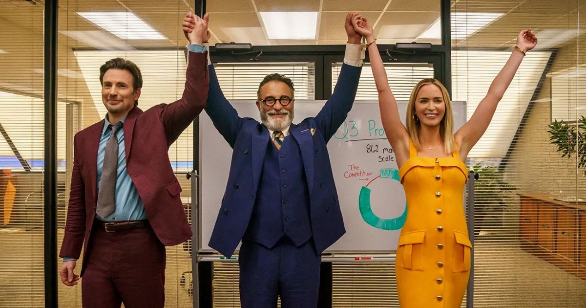 Two men and a woman raise their hands in celebration in a corporate office.