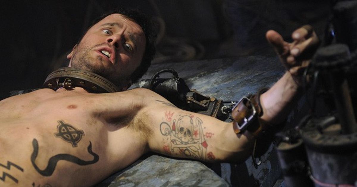 Joris Jarsky as Seth Baxter, a man with tattoos all over his body, strapped to a stone slab in Saw V