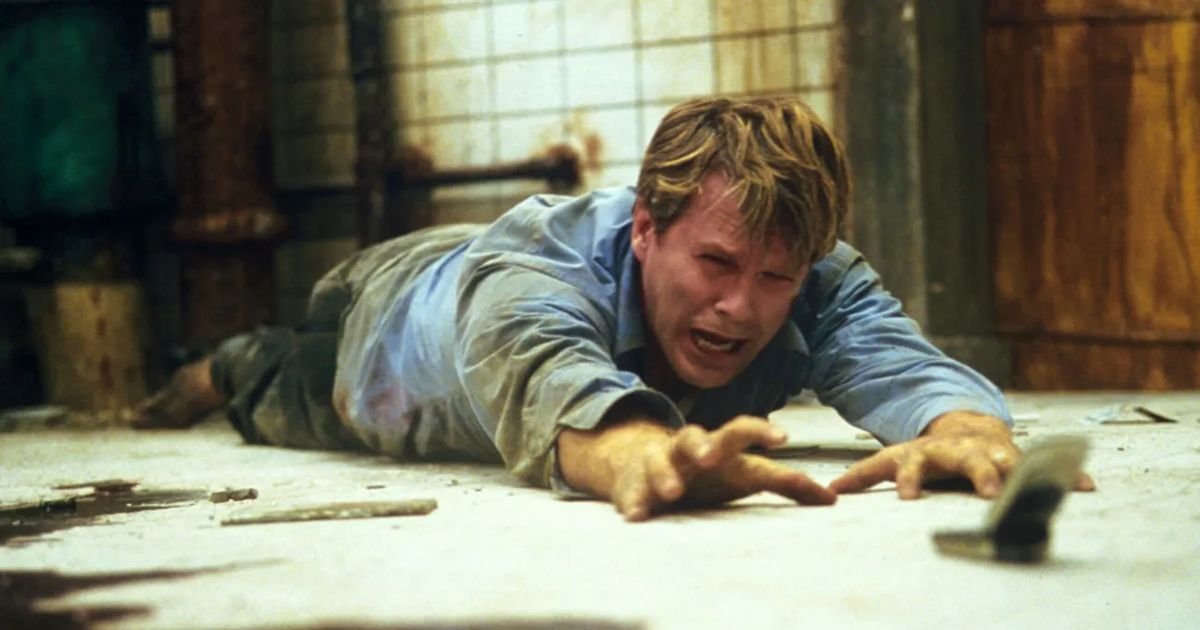 Lawrence reaches for his phone in Saw.