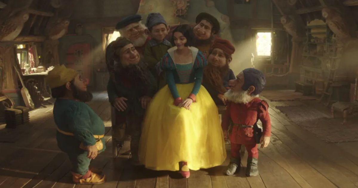 Rachel Zegler como Branca de Neve com outros sete personagens em uma pequena casa de campo em Branca de Neve.