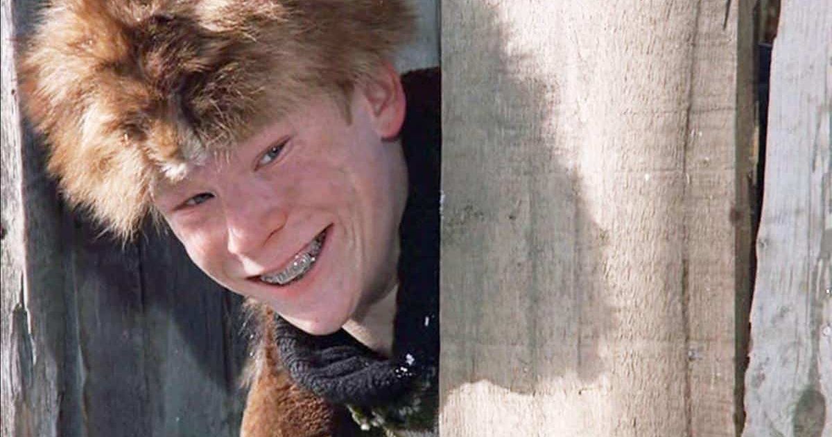 Zack Ward as Scut Markus in A Christmas Story smiling behind a fence