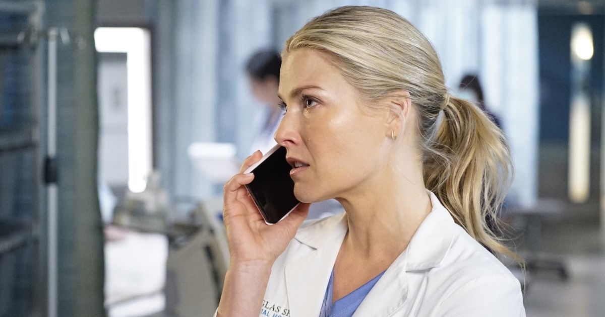 Ali Larter as Grace Sawyer wearing a white doctors outfit with scrubs on, talking on the phone with someone in the hospital in The Rookie Season 2