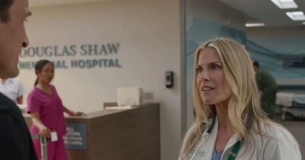 Ali Larter as Grace Sawyer in The Rookie Season 2, wearing a white hospital outfit with other workers in the hospital behind her.