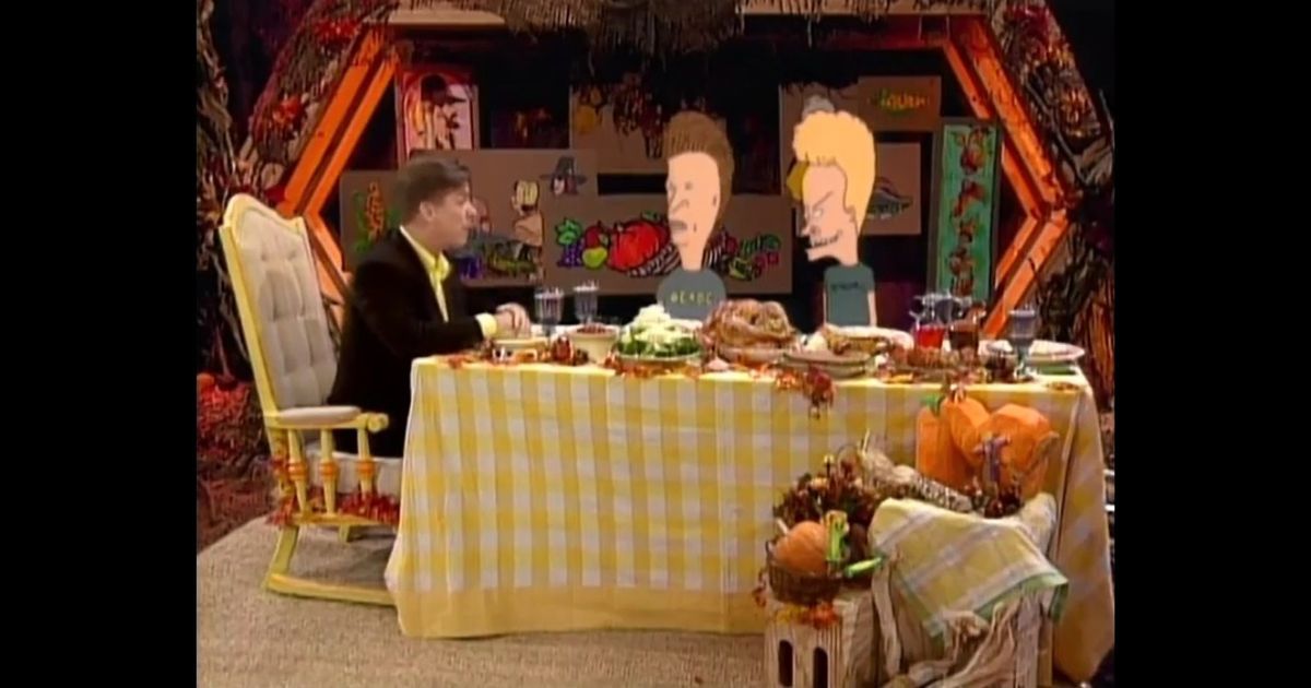 Beavis and Butthead do Thanksgiving the two sit at a table superimposed onto a real live shot with a man for Thanksgiving dinner