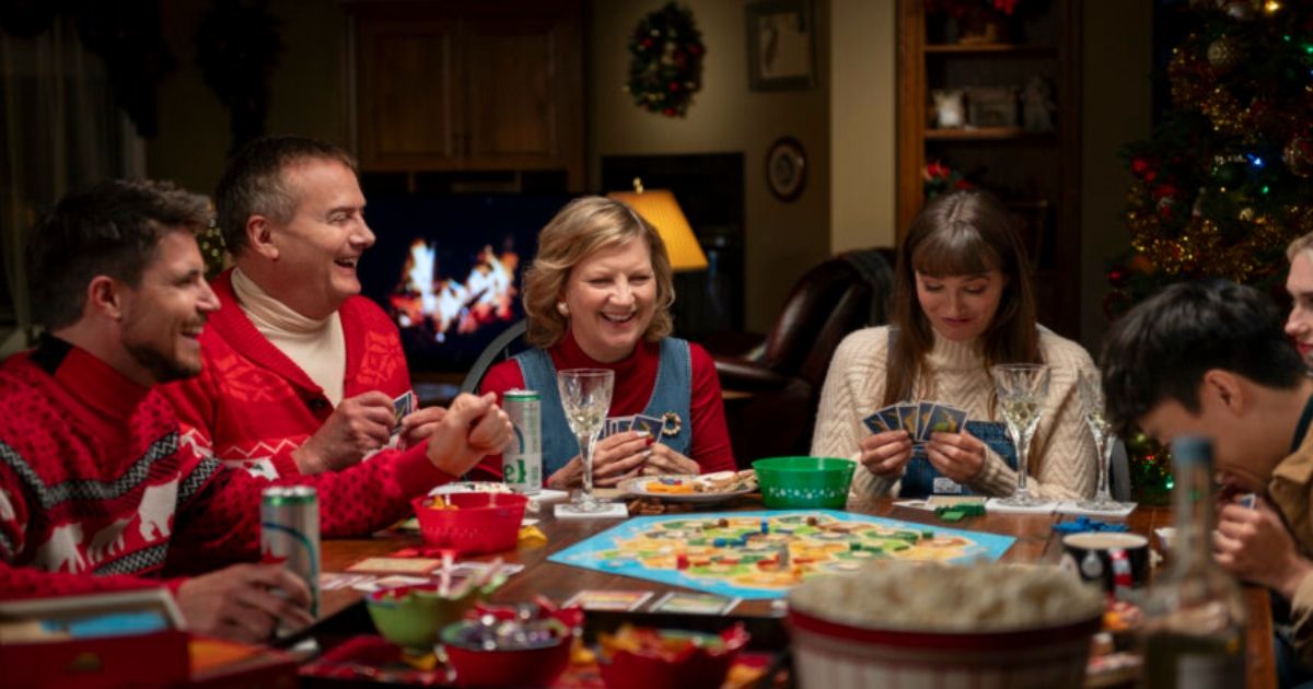 family sitting round table at Christmas playing board games in Exmas