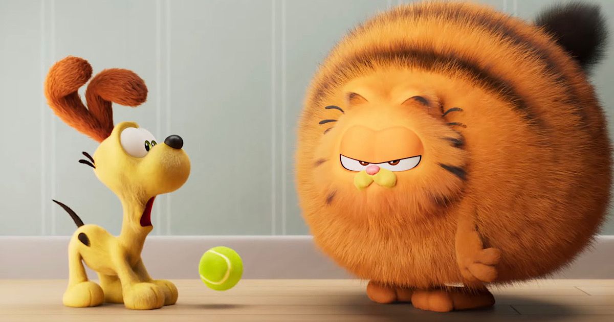 Chris Pratt's Garfield with his fur fluffed up next to Odie and a tennis ball, as Odie looks shocked with Garfield's fur. 