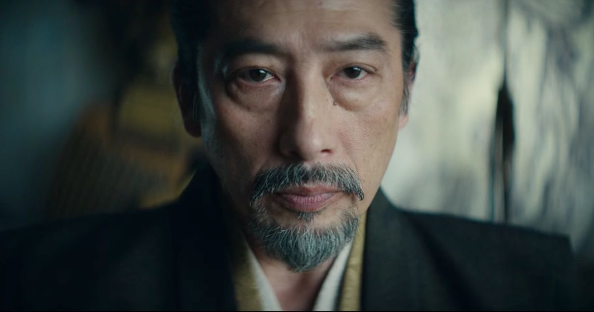 Hiroyuki Sanada in Shogun wearing a black shirt with layers staring past the camera.