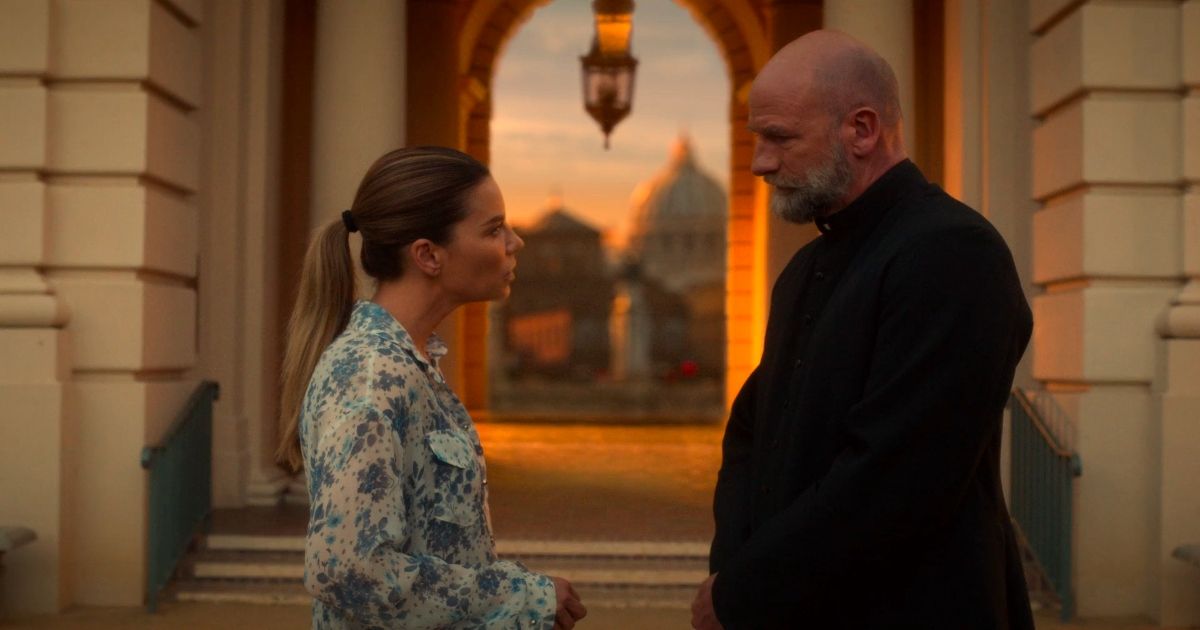 Chloe consults a priest outside a white-brick building