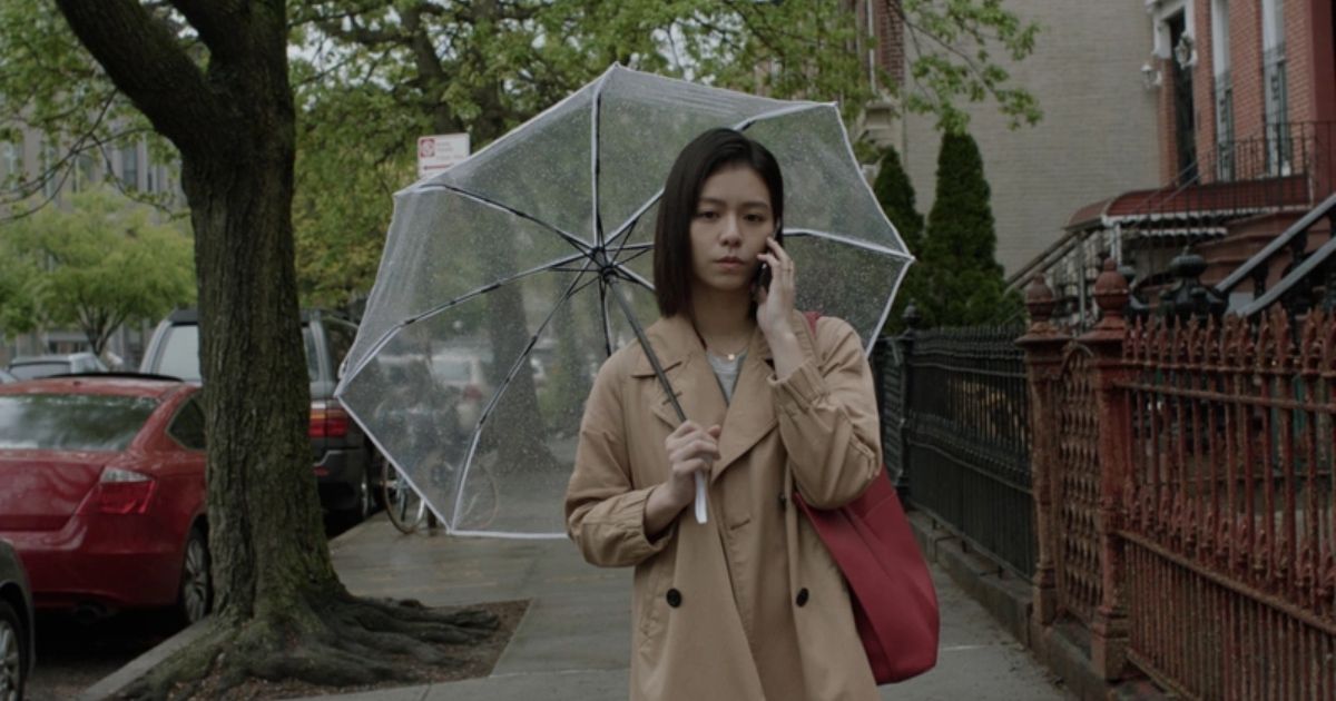 Mulher com guarda-chuva ao telefone em My Heavenly City