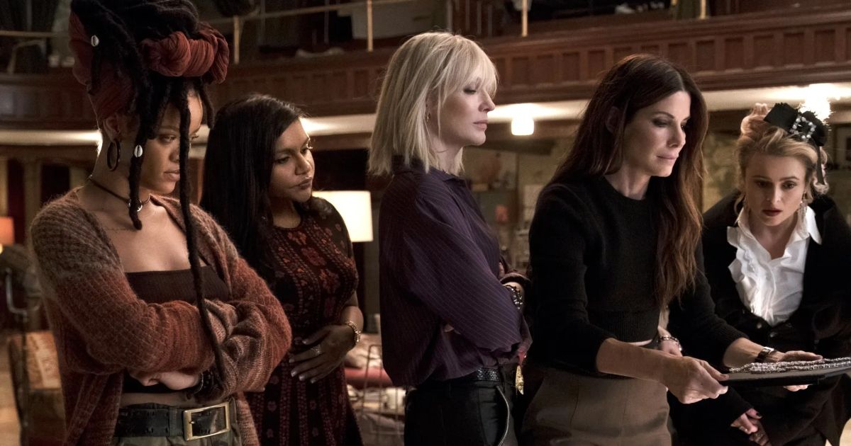 The ensemble cast of Ocean's 8 looking at a diamond necklace.