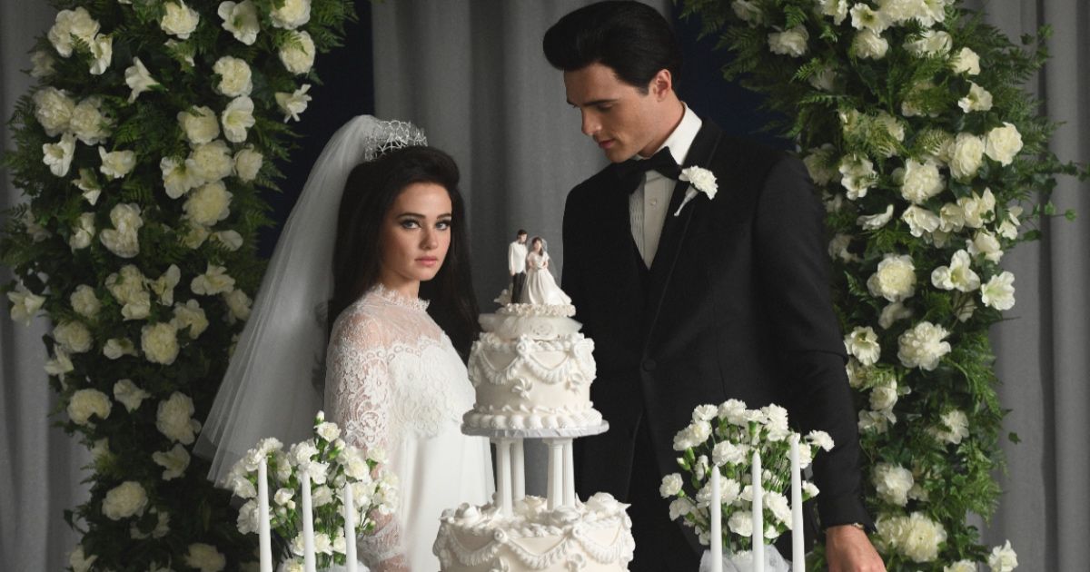 Jacob Elordi as Elvis and Cailee Spaeny as Priscilla getting married wearing a tuxedo and wedding dress with their cake in front of them in Priscilla.