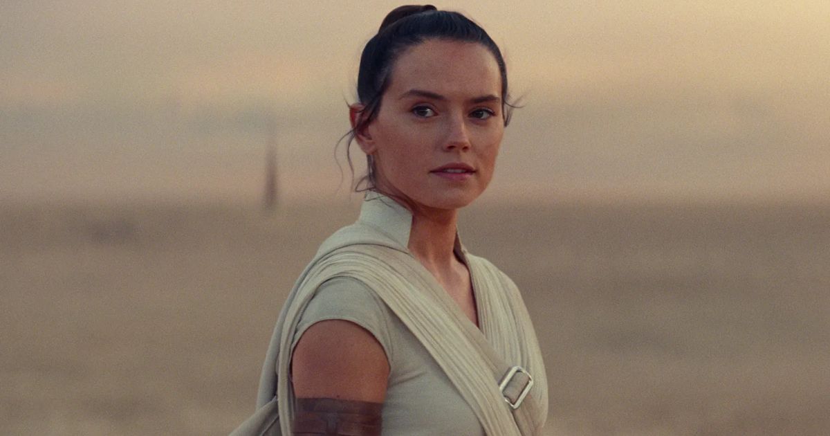 Daisy Ridley as Rey Skywalker in Star Wars, standing in the desert of Tatooine, looking at something off-screen, wearing tan jedi robes in The Rise of Skywalker