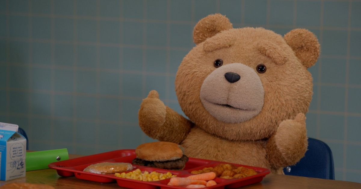 Ted na série prequela Peacock comendo hambúrguer com polegares para cima