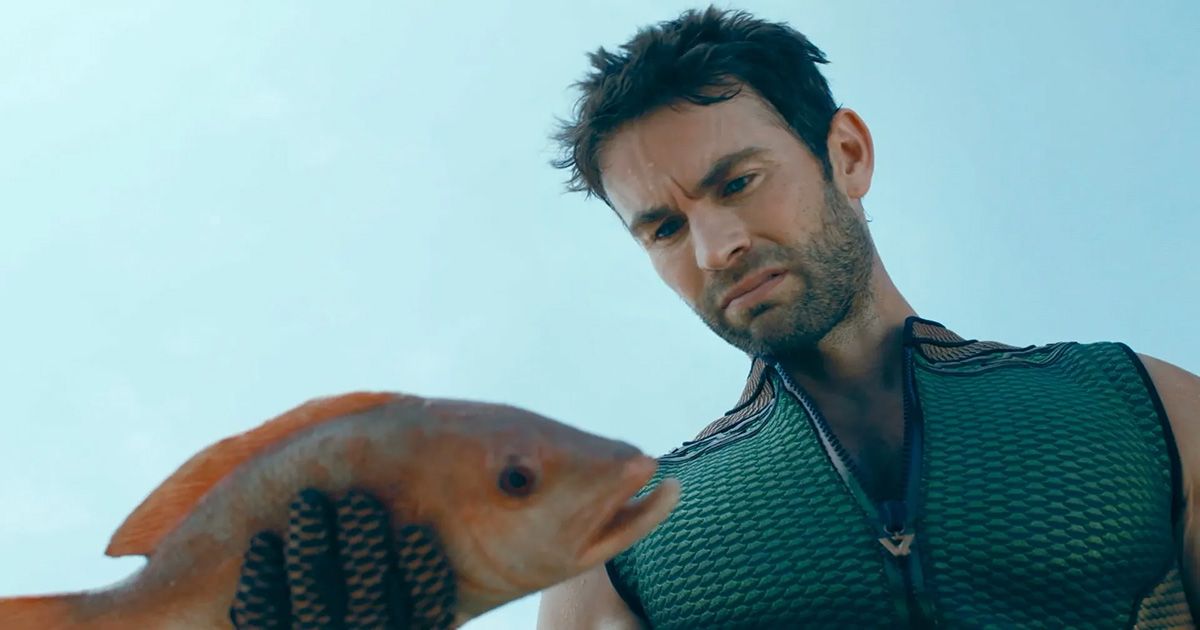 Chace Crawford as The Deep in his aqua super suit with scales, staring at a dead fish in The Boys
