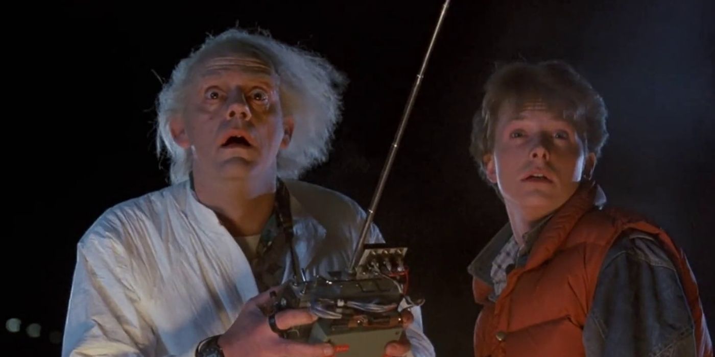 Christopher Lloyd as Doc Brown holds a remote control device as he stands next to Michael J. Fox's Marty McFly in Back to the Future