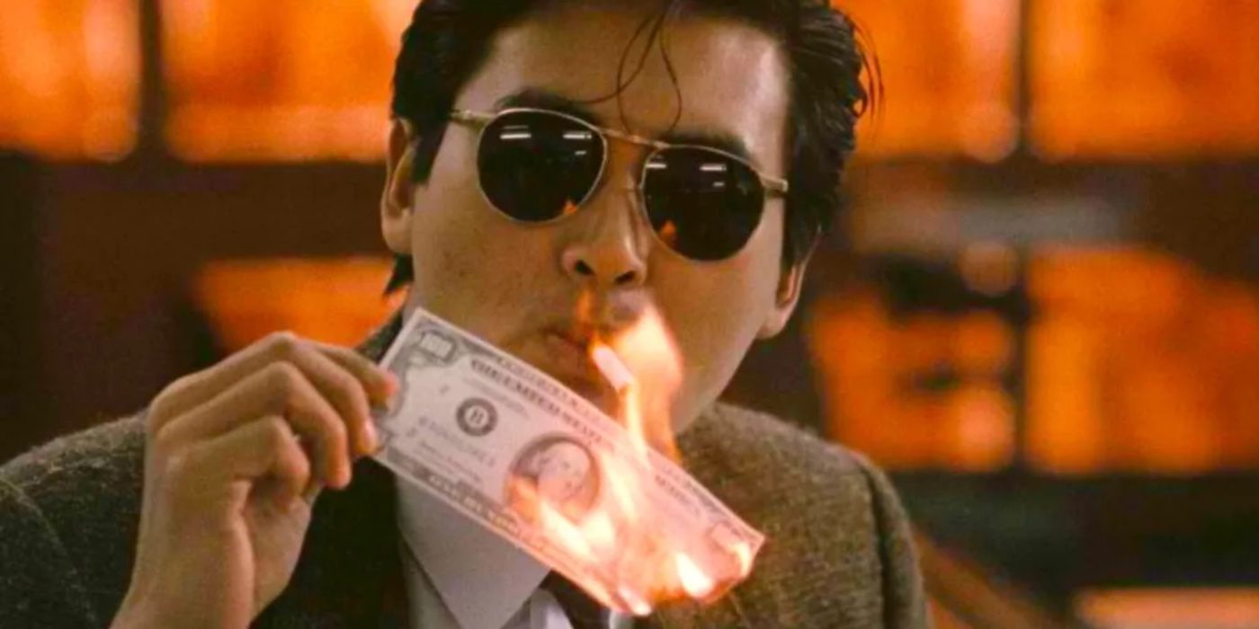 A man in sunglasses burns a 100-dollar bill