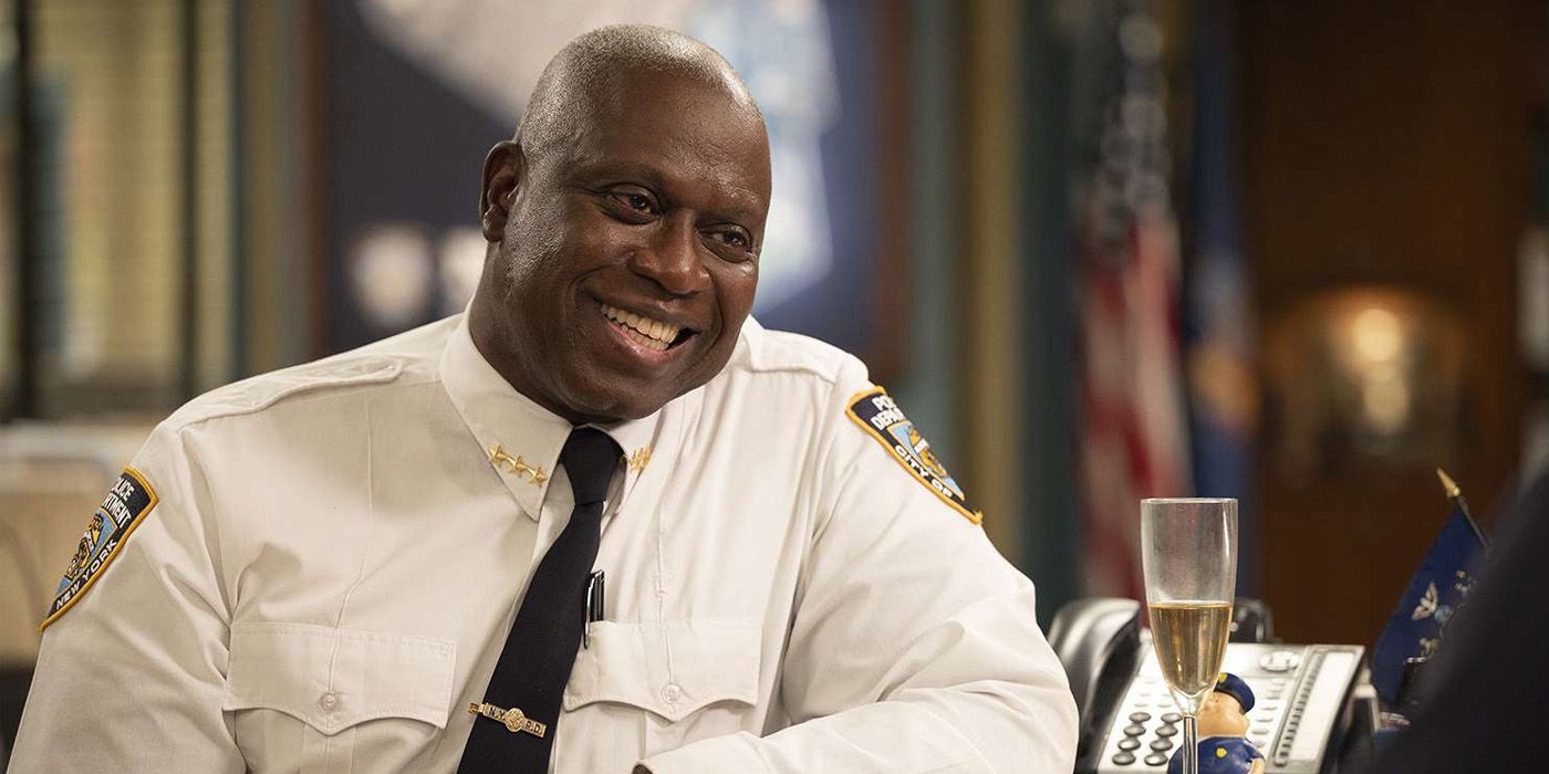 Andre Braugher as Raymond Holt in his police uniform drinking a glass of champagne and smiling in Brooklyn Nine-Nine