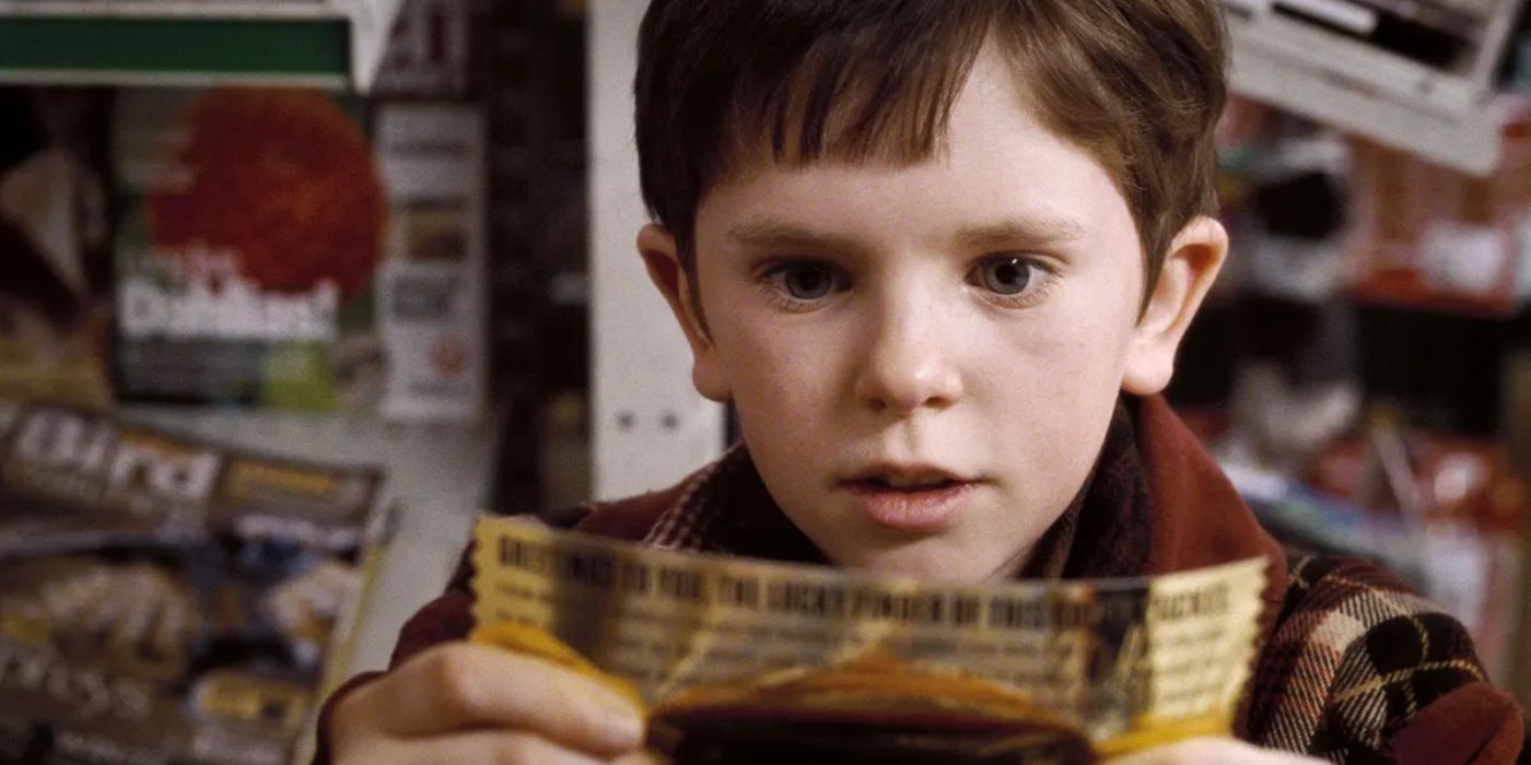 Um menino parece animado enquanto segura um bilhete dourado.