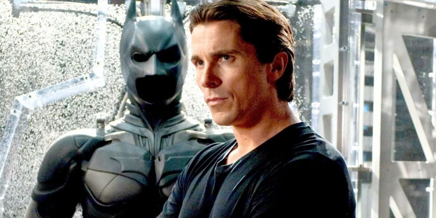 Christian Bale as Batman in front of the bat suit