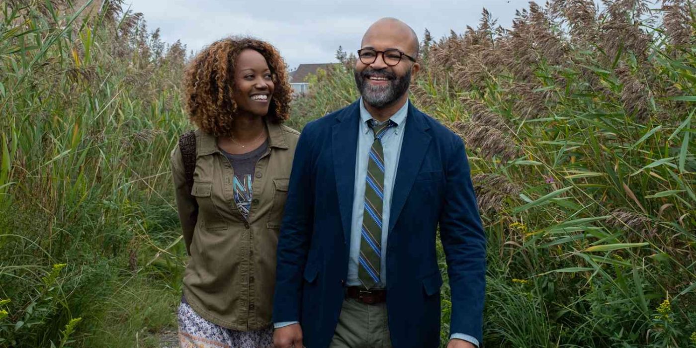 A Black man and woman strolling through a field with tall grass.