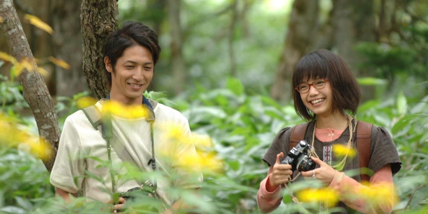 Um jovem casal japonês tirando fotos em uma floresta