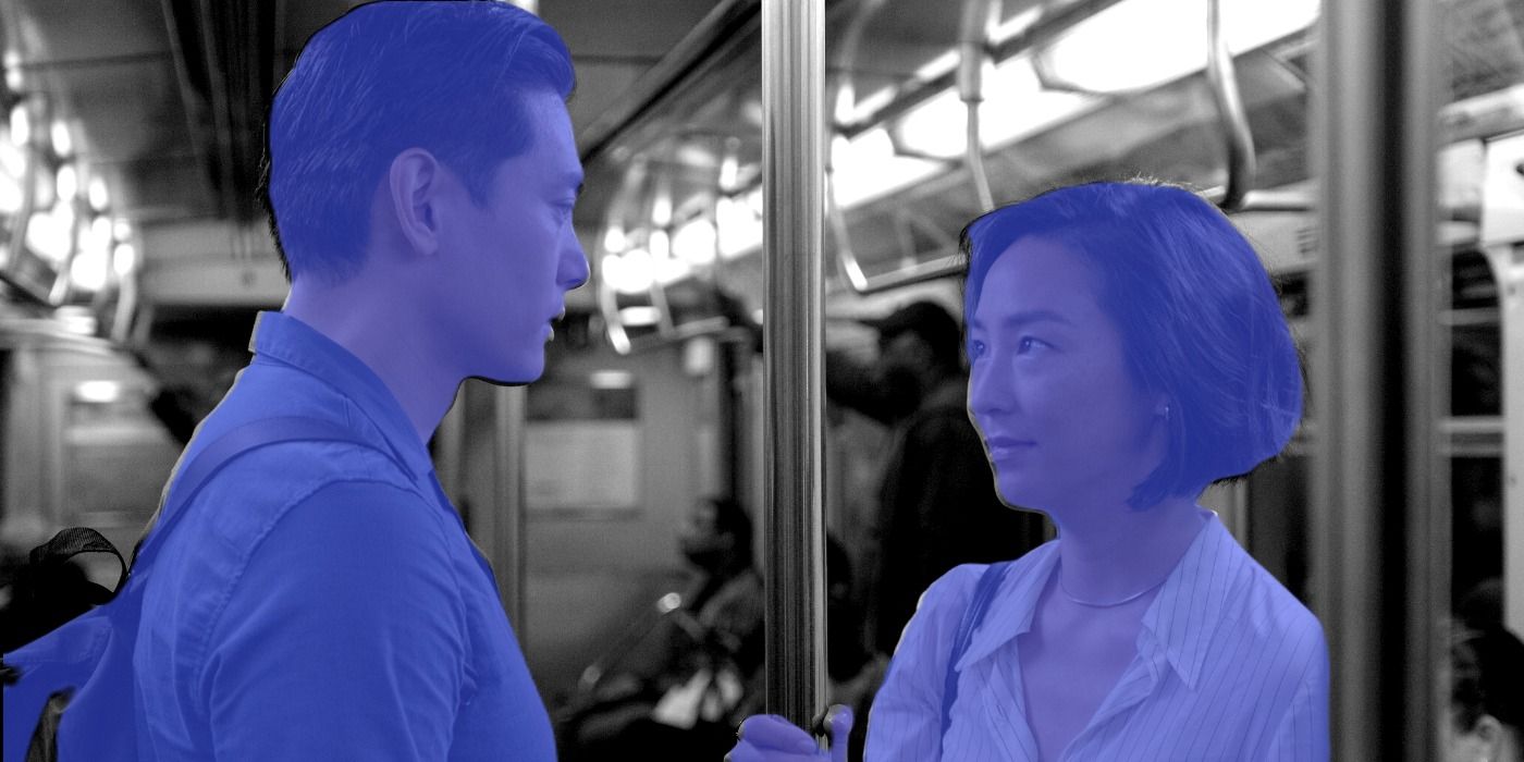 Past Lives characters in blue stare at each other in black and white subway train
