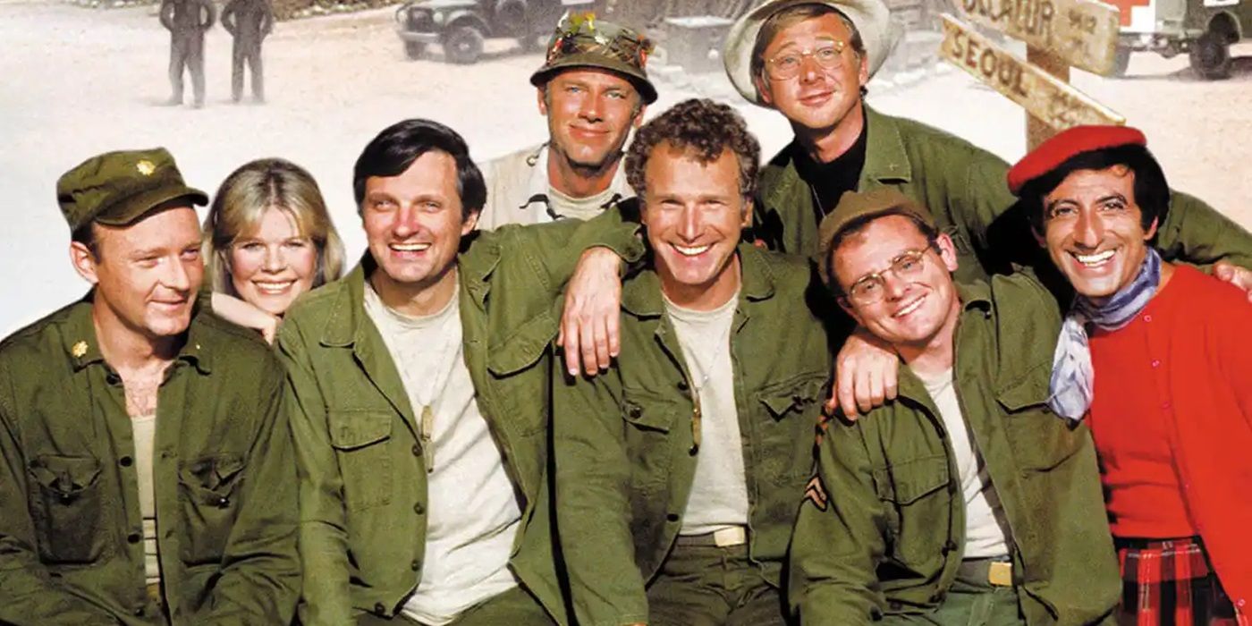 The main cast of M*A*S*H posing together and laughing.