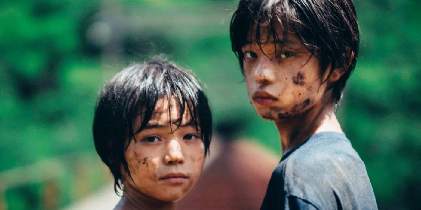Two Japanese boys with muddy faces look directly at the camera.
