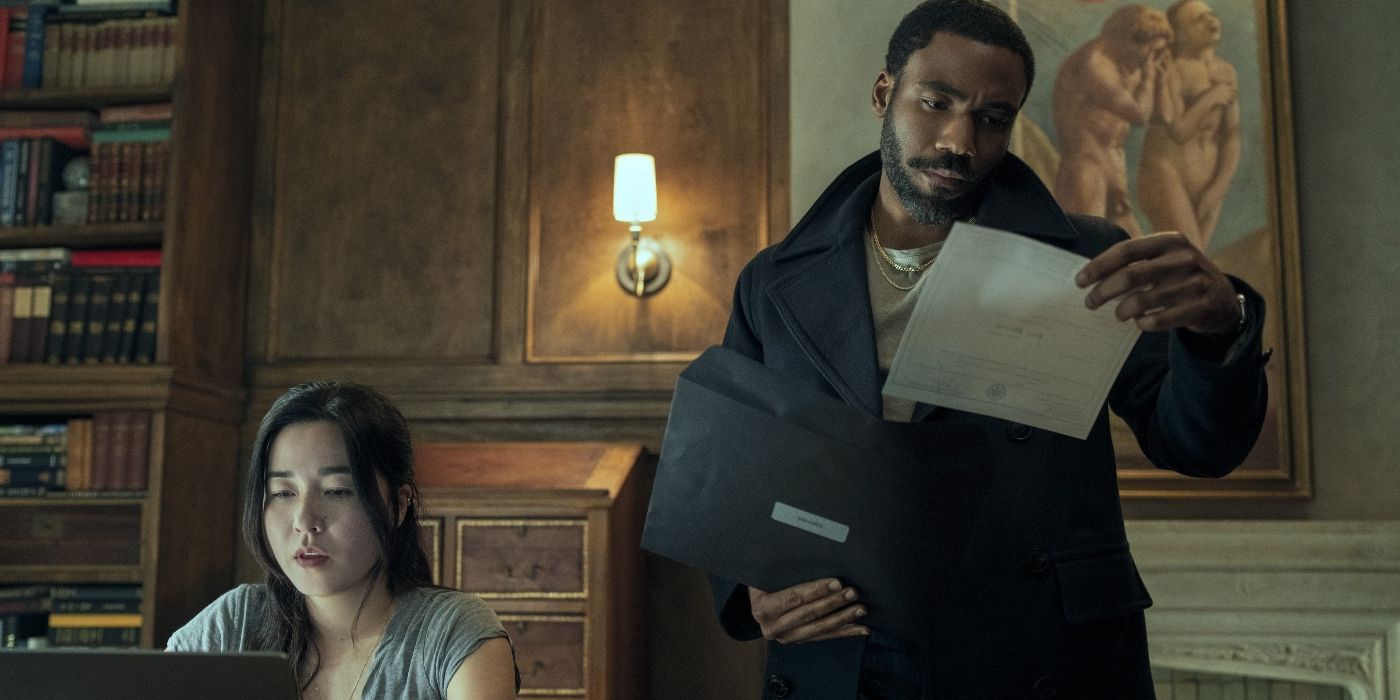 Donald Glover as John and Maya Erskine as Jane in an office looking at documents in Mr. & Mrs. Smith