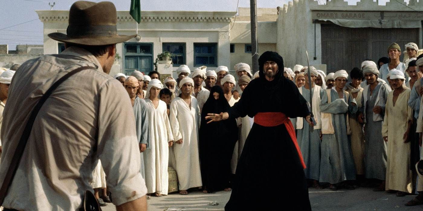 Indiana Jones na frente do vilão com uma espada enquanto uma multidão assiste aos invasores da arca perdida