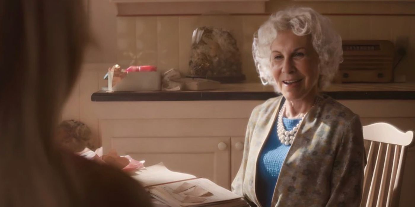 Rhea Perlman as Ruth Handler in Barbie (2023), sitting at her kitchen table.