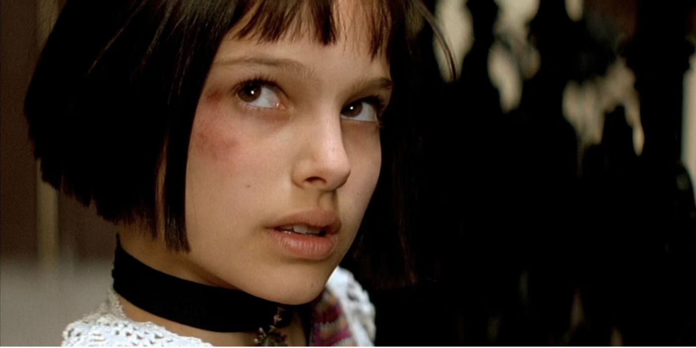 Natalie Portman as Mathilda wearing a necklace looking up at someone off-screen in Leon: The Professional