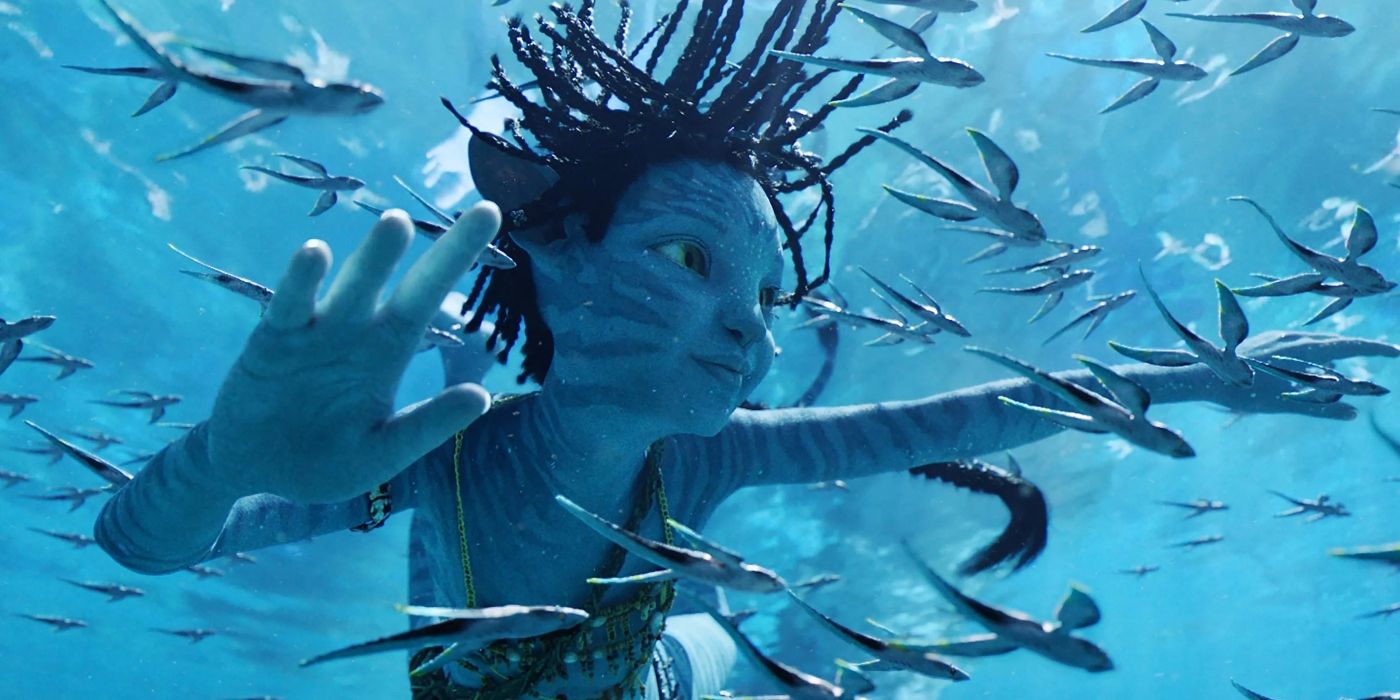 Trinity Bliss as Tuktirey swimming in the ocean underwater with small alien fish all around her in Avatar: The Way of Water