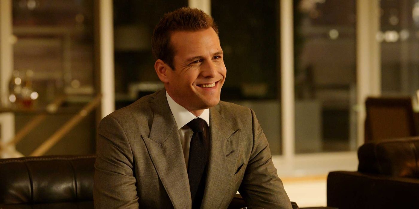 Gabriel Macht as Harvey Specter, wearing a grey suit and a massive grin, in Suits