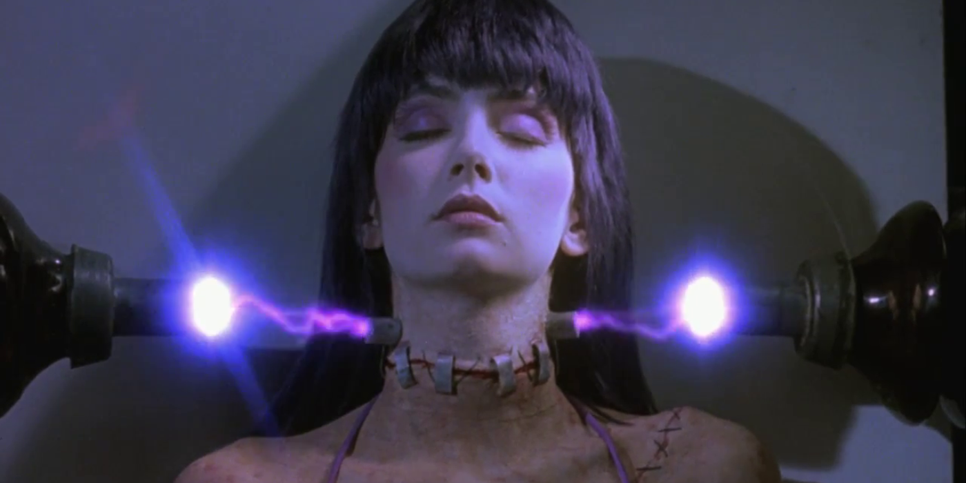 A woman with her neck stitched to her body is lying between two bright beams of light.