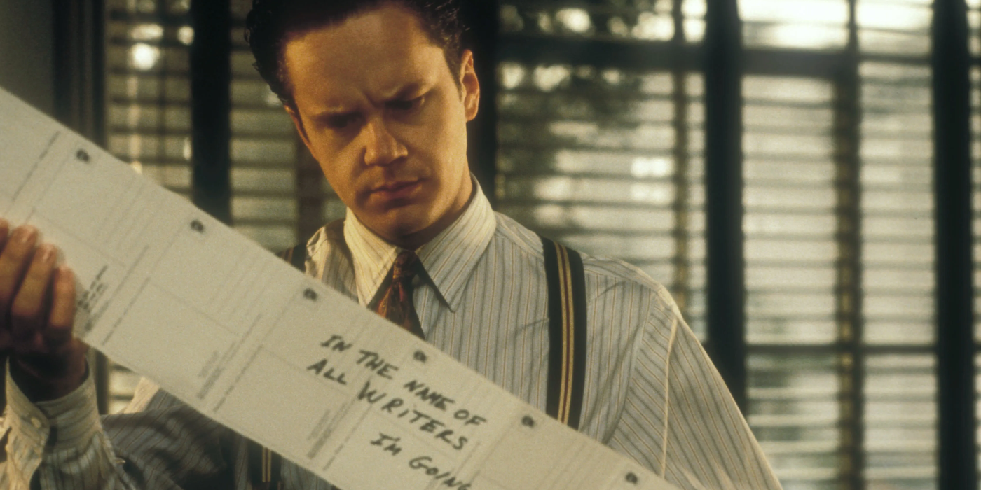  Griffin is wearing a pinstripe shirt with suspenders. He is holding up a set of postcards connected to one another. Dark blinds are open behind him.