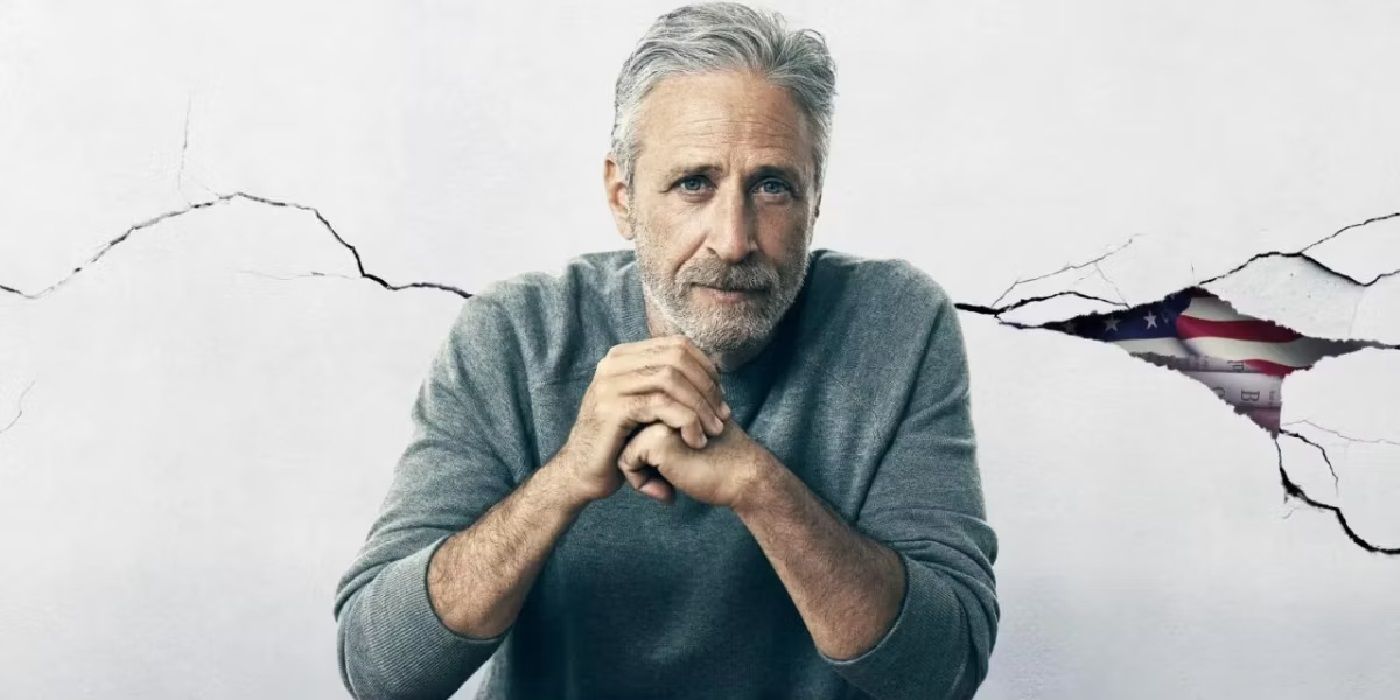 Jon Stewart with his hands clasped looking at the camera
