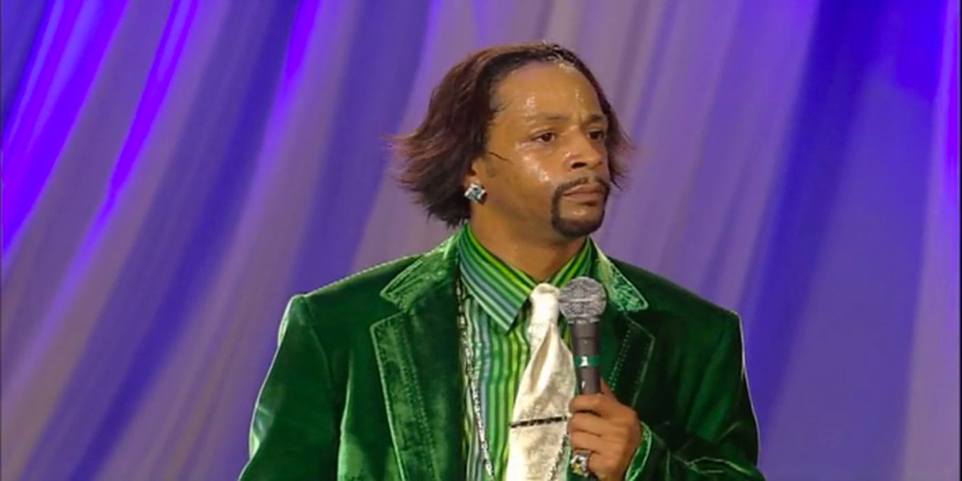 Katt Williams in a green suit holding a microphone on stage for the pimp chronicles pt 1 HBO