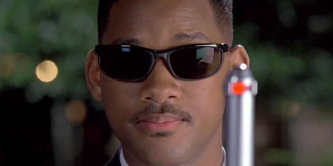 Will Smith as Agent J, wearing his signature shades and holding up a cylindrical device, in Men in Black